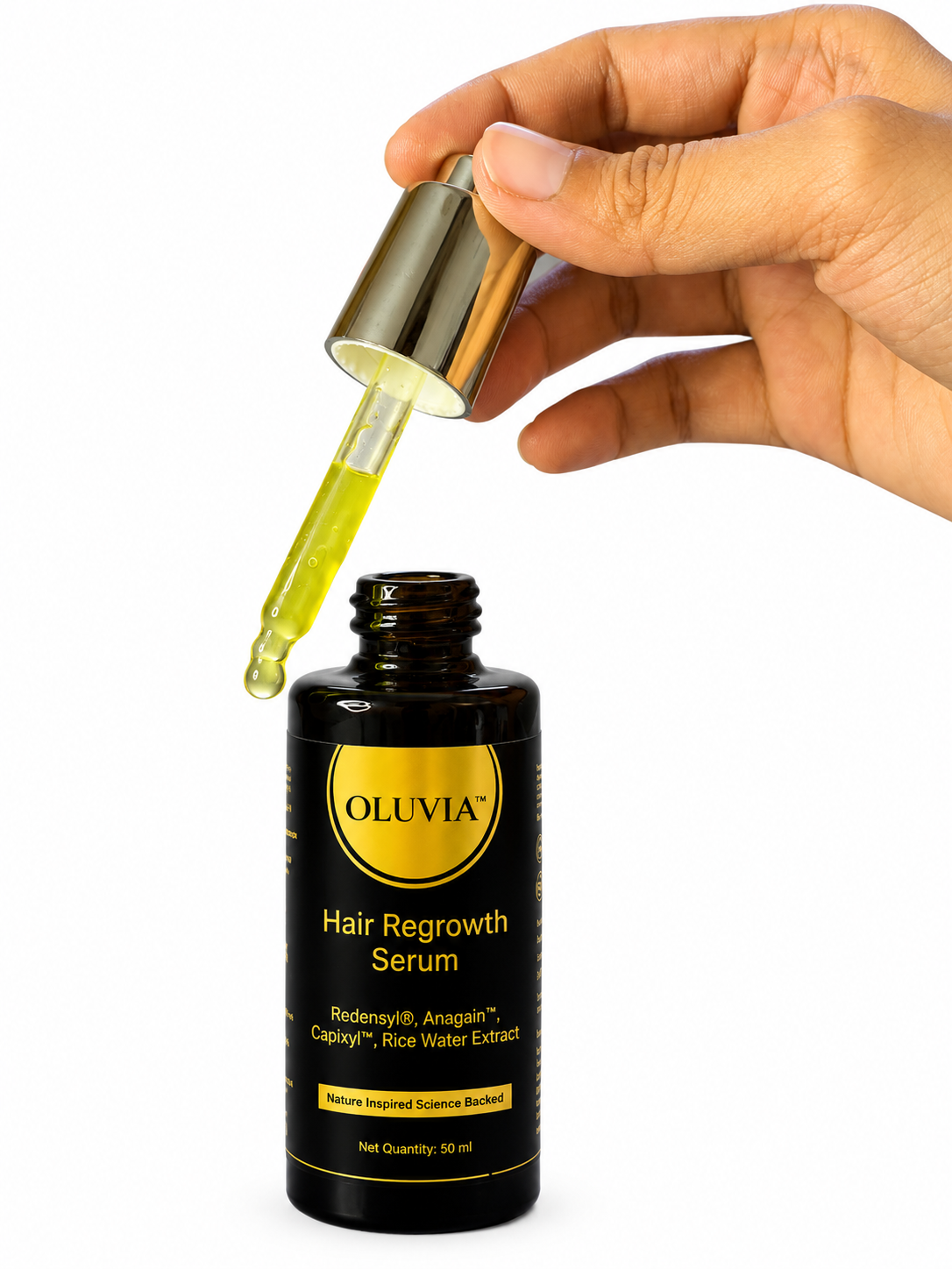 A hand holding a gold-capped glass dropper above an open black bottle of Oluvia Hair Regrowth Serum, with a clear droplet of yellow-green liquid hanging between the dropper and bottle on a white background.